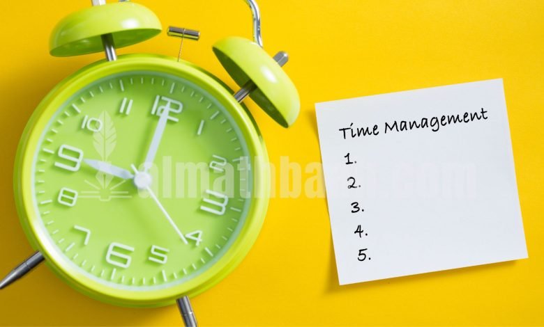 Jam alarm berwarna hijau dengan kertas catatan kecil bertuliskan "management", ilustrasi pengingat manajemen waktu.